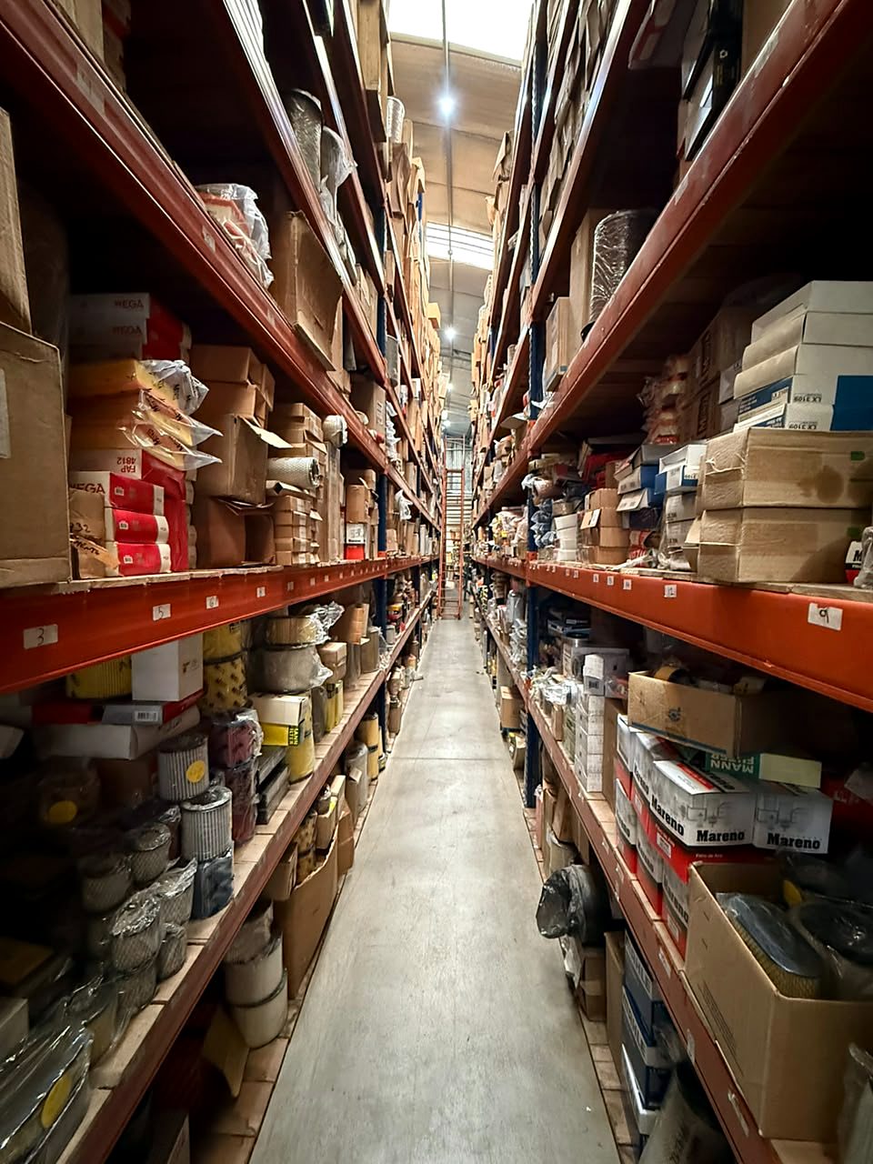 Pasillo del depósito con estanterías altas de filtros Wega, Mann y Mareno